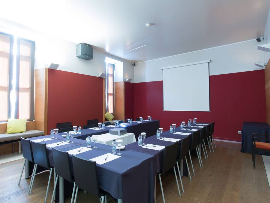 Una sala conferenze con un lungo tavolo, sedie, uno schermo per proiettore e un'ampia finestra.