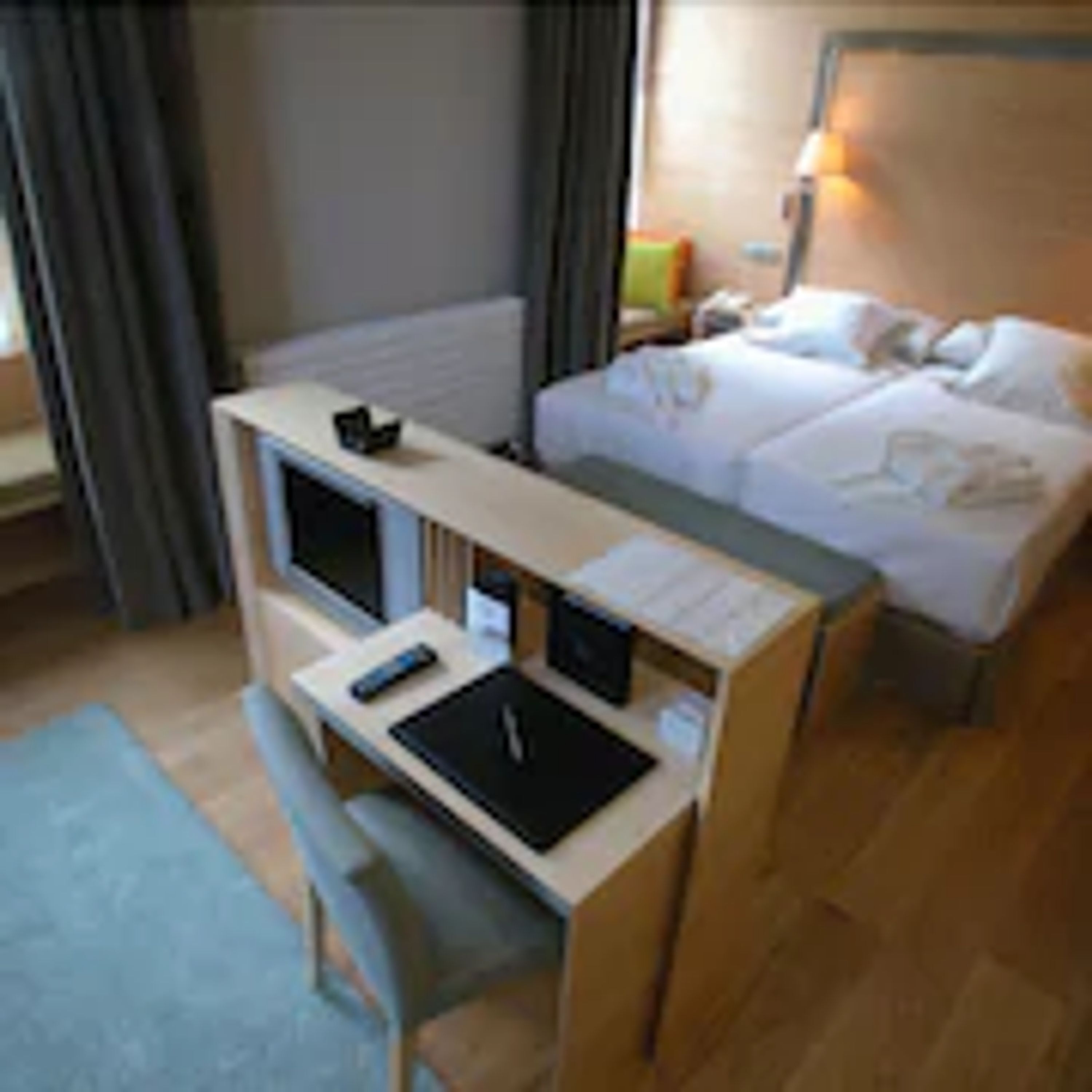 Una habitación de hotel con una cama, un escritorio con una computadora y una silla.