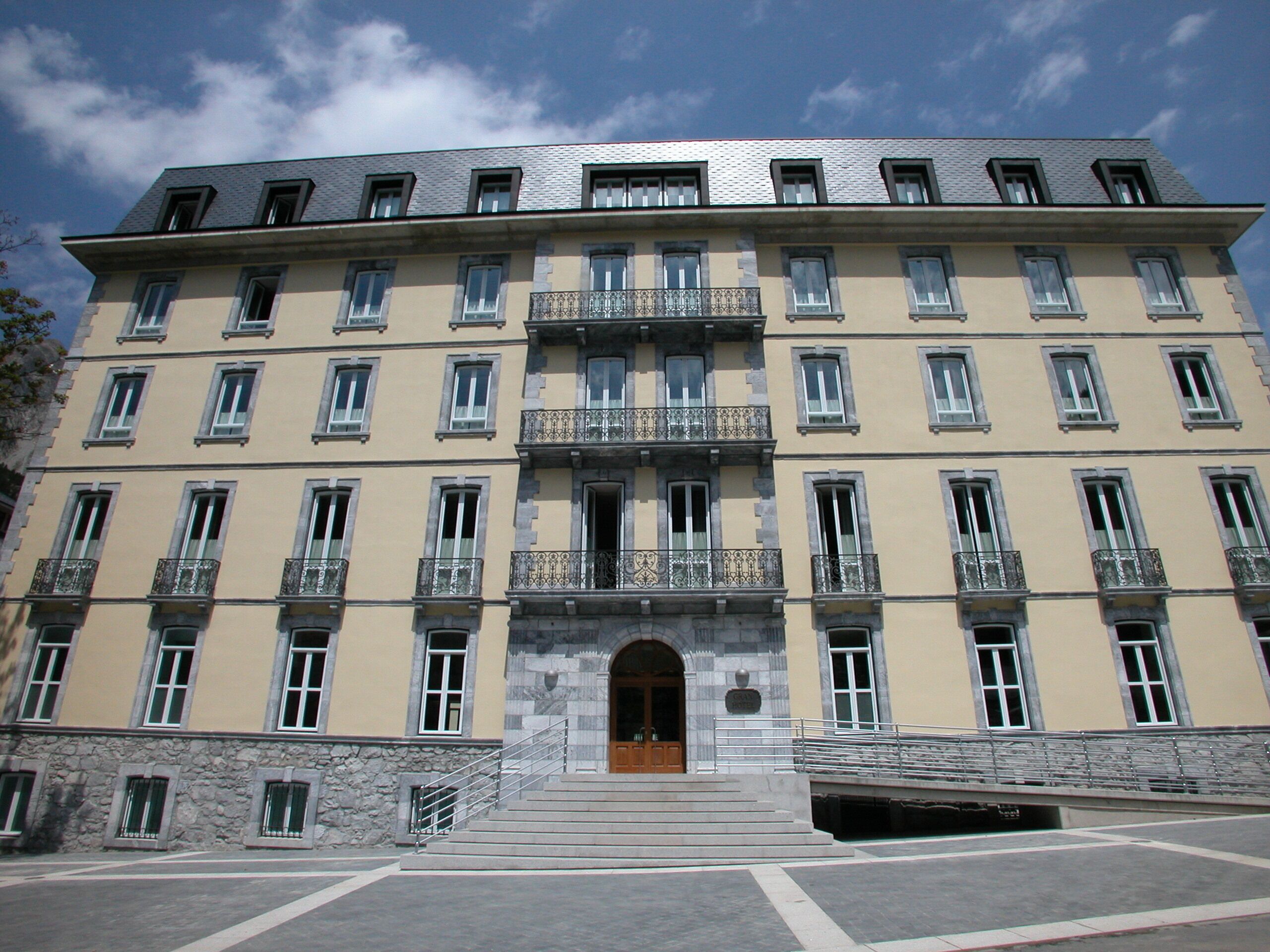 Un edificio de varios pisos con fachada simétrica, amplias ventanas y una entrada central con escalinata.