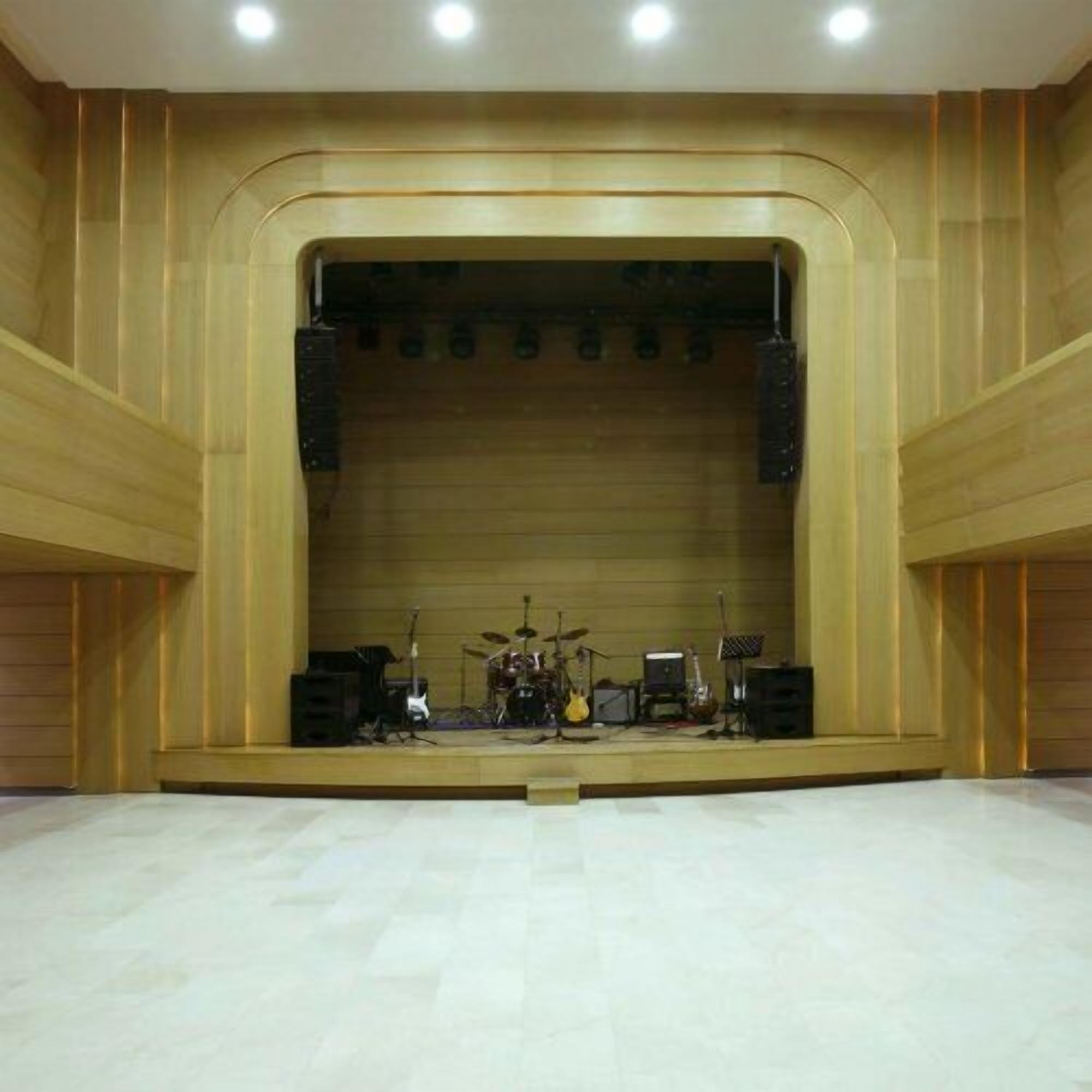 A spacious auditorium with a stage, equipped with musical instruments and speakers.
