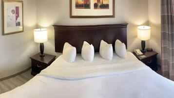 A hotel room with a large bed, two bedside tables with lamps, a TV, and a painting on the wall.