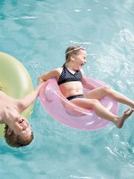 Una piscina al aire libre, sillones reclinables de piscina