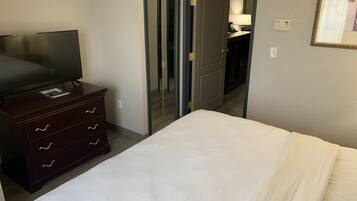 Habitación de hotel con cama, televisor en una cómoda y espejo en la pared.