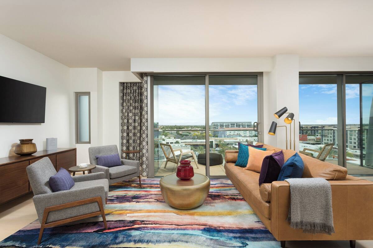 Una sala de estar moderna con un sofá, sillones, una mesa de centro y un ventanal con vistas a la ciudad.