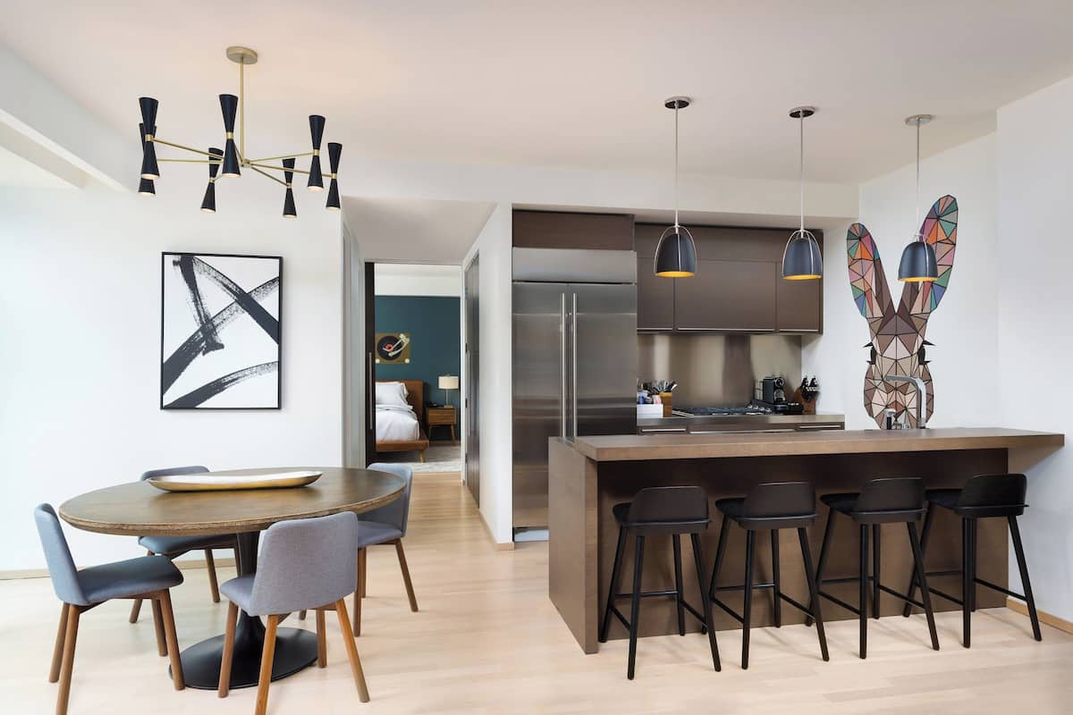 Una cocina moderna con una isla central, taburetes de bar e iluminación colgante.