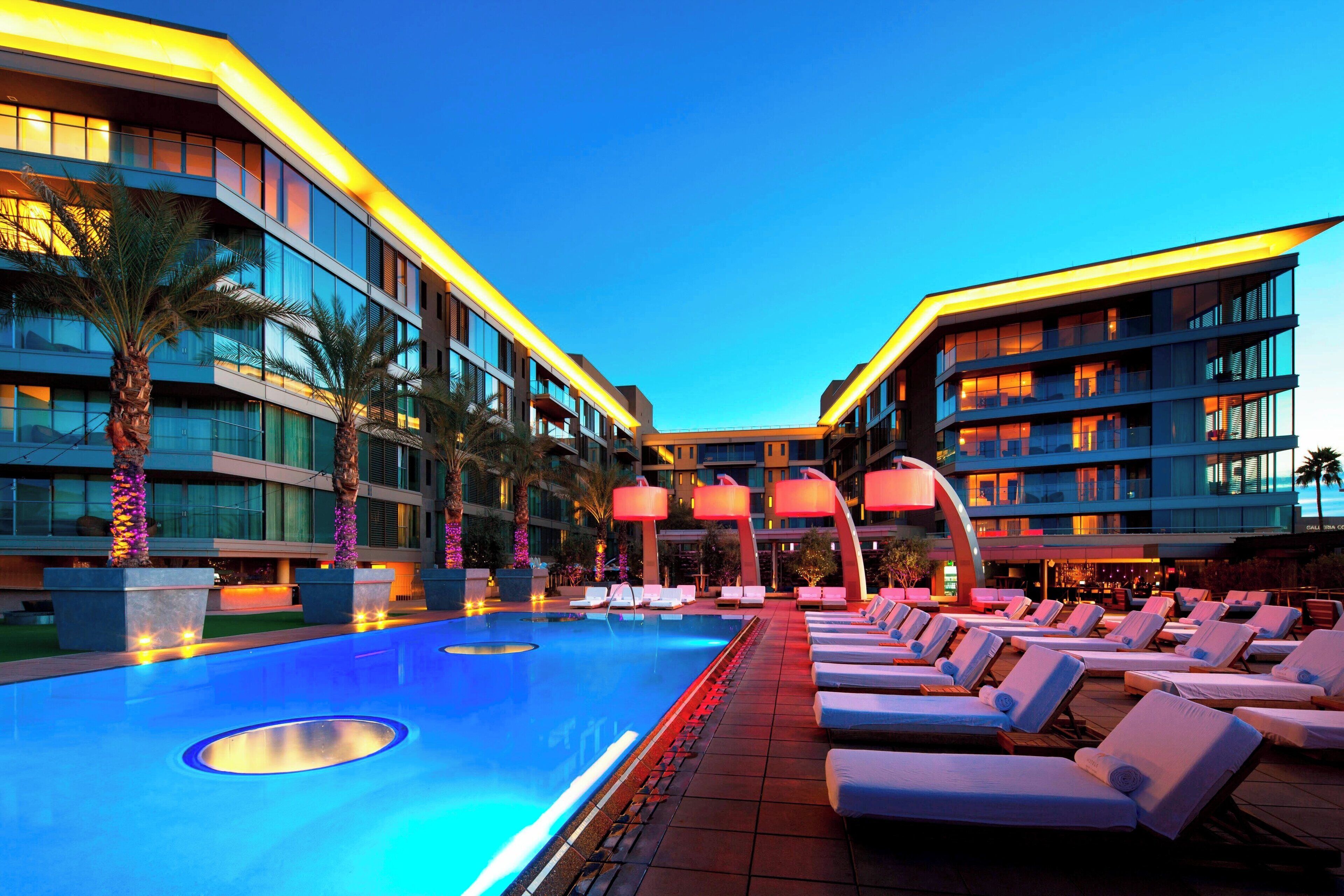 Una piscina al aire libre, camas de piscina con cargo, sombrillas