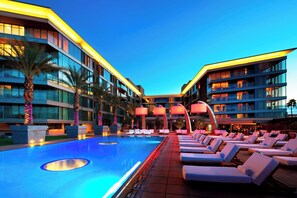 Una piscina al aire libre, camas de piscina con cargo, sombrillas