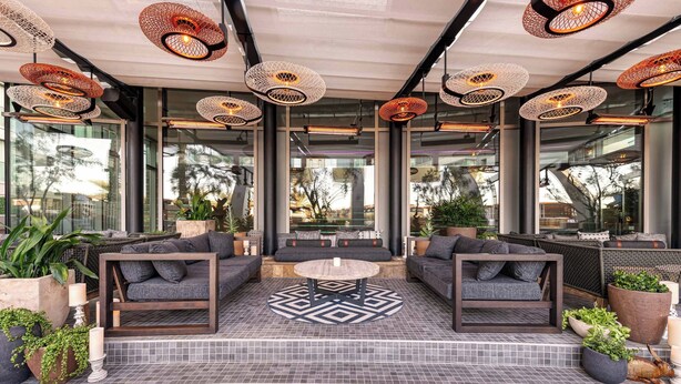 An outdoor seating area with modern furniture, large windows, and decorative lighting. - W Scottsdale (Scottsdale)