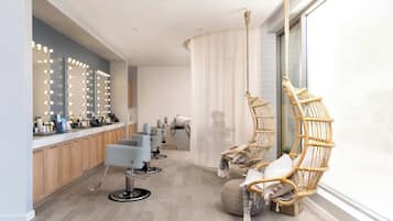 Experience a professional atmosphere at this salon, featuring rows of hairdressing stations with chairs, mirrors, and vanities.