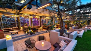 An outdoor seating area with round tables and sofas, surrounded by potted plants and trees. - W Scottsdale (Scottsdale)