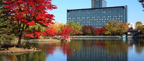 A building with a modern architectural design, situated near a body of water with reflections of surrounding trees.