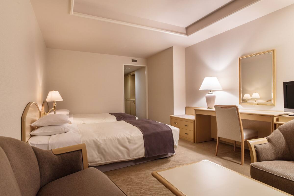 A hotel room with a bed, desk, chair, and a television.