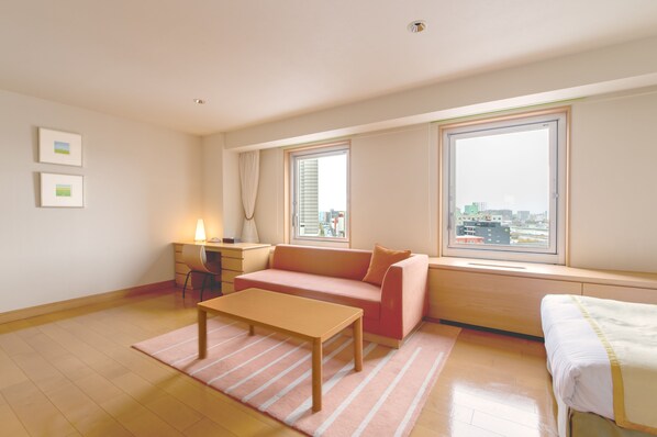 A modern living room with a sofa, a small table, a desk, and a window with a city view. - Sapporo Park Hotel (Sapporo)