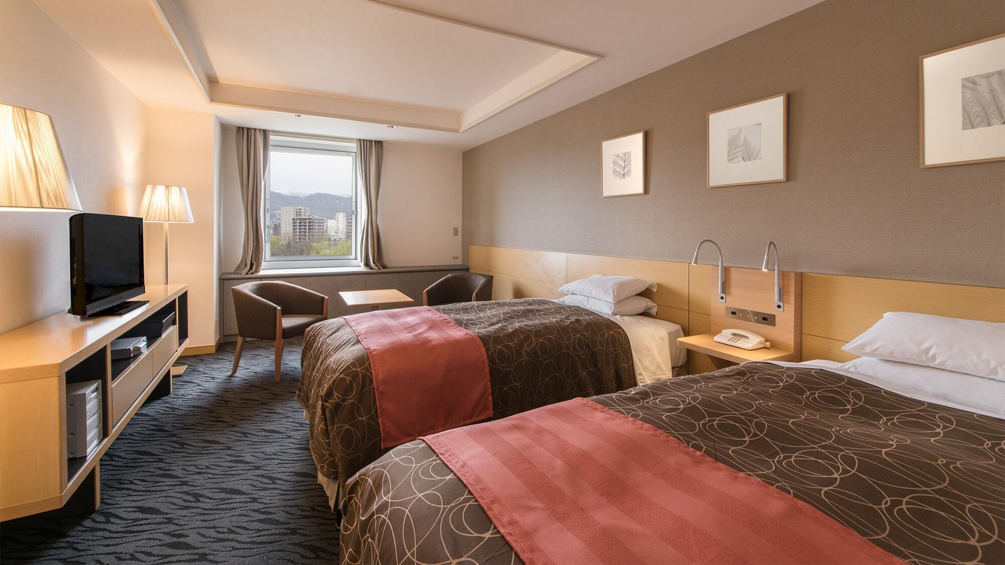 Een hotelkamer met twee bedden, een bureau, een televisie en een raam met gordijnen.