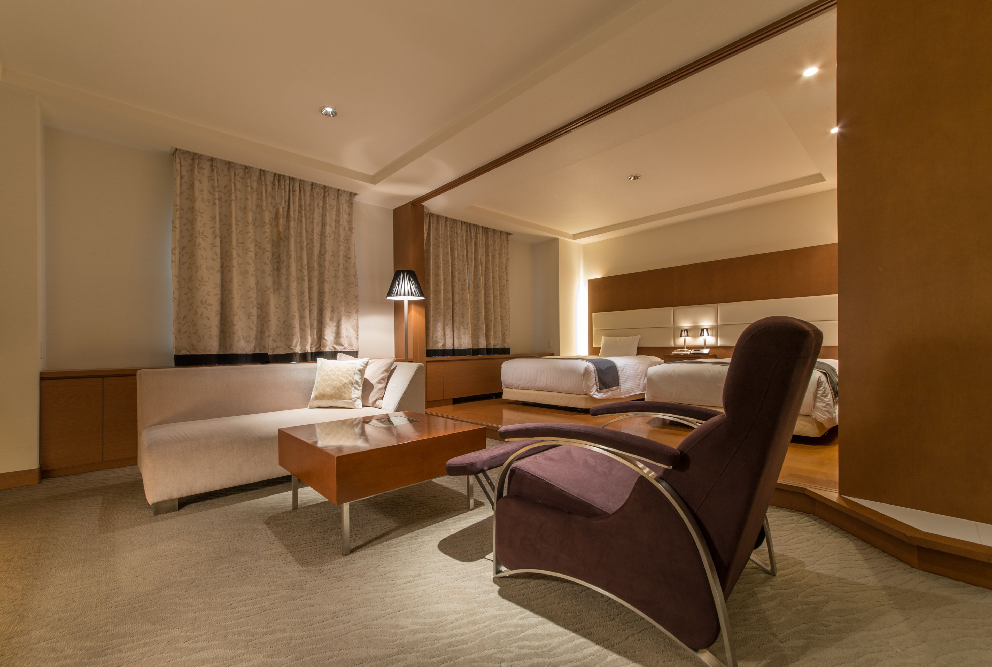 A hotel room with a sofa, a chair, a bed, and a desk.