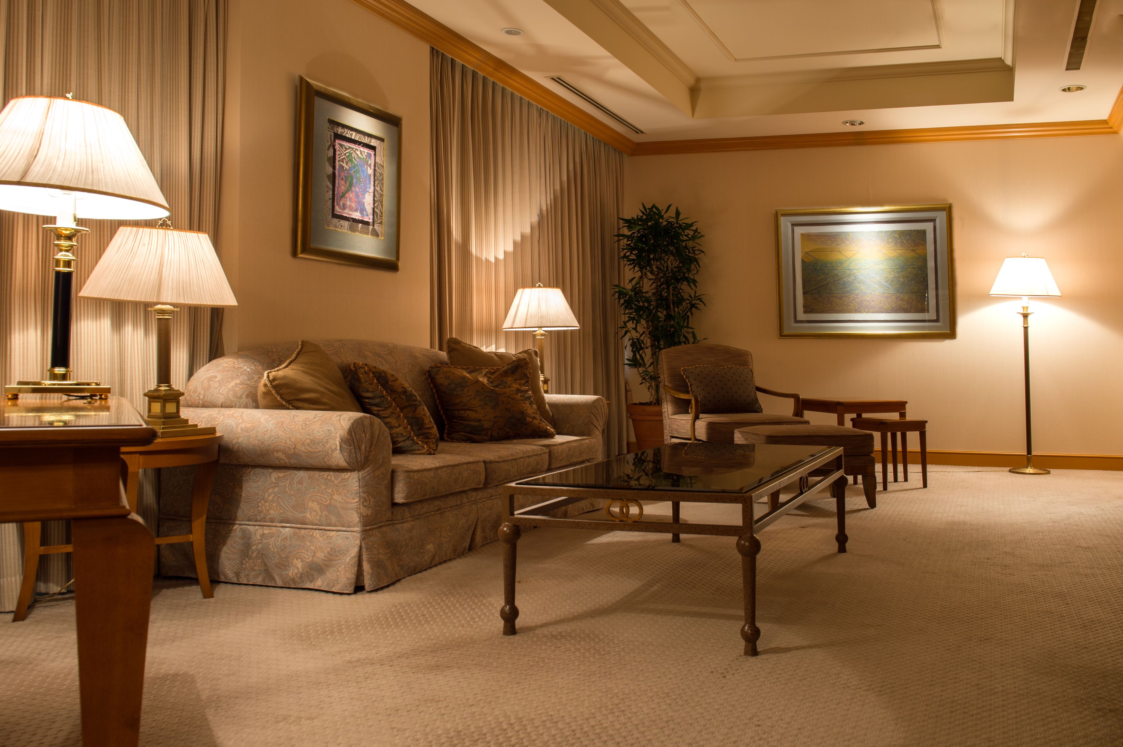 A well-lit living room with a sofa, armchairs, a coffee table, and lamps.