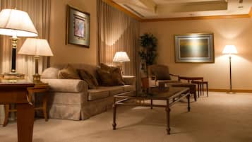 A well-lit living room with a sofa, armchairs, a coffee table, and lamps.