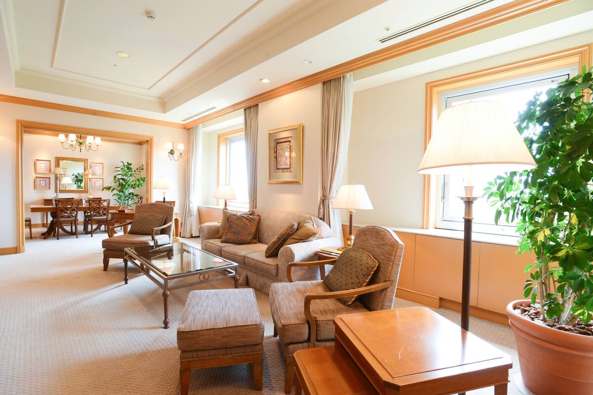 A spacious living room with a sofa, armchairs, a coffee table, and a dining area with chairs and a table.