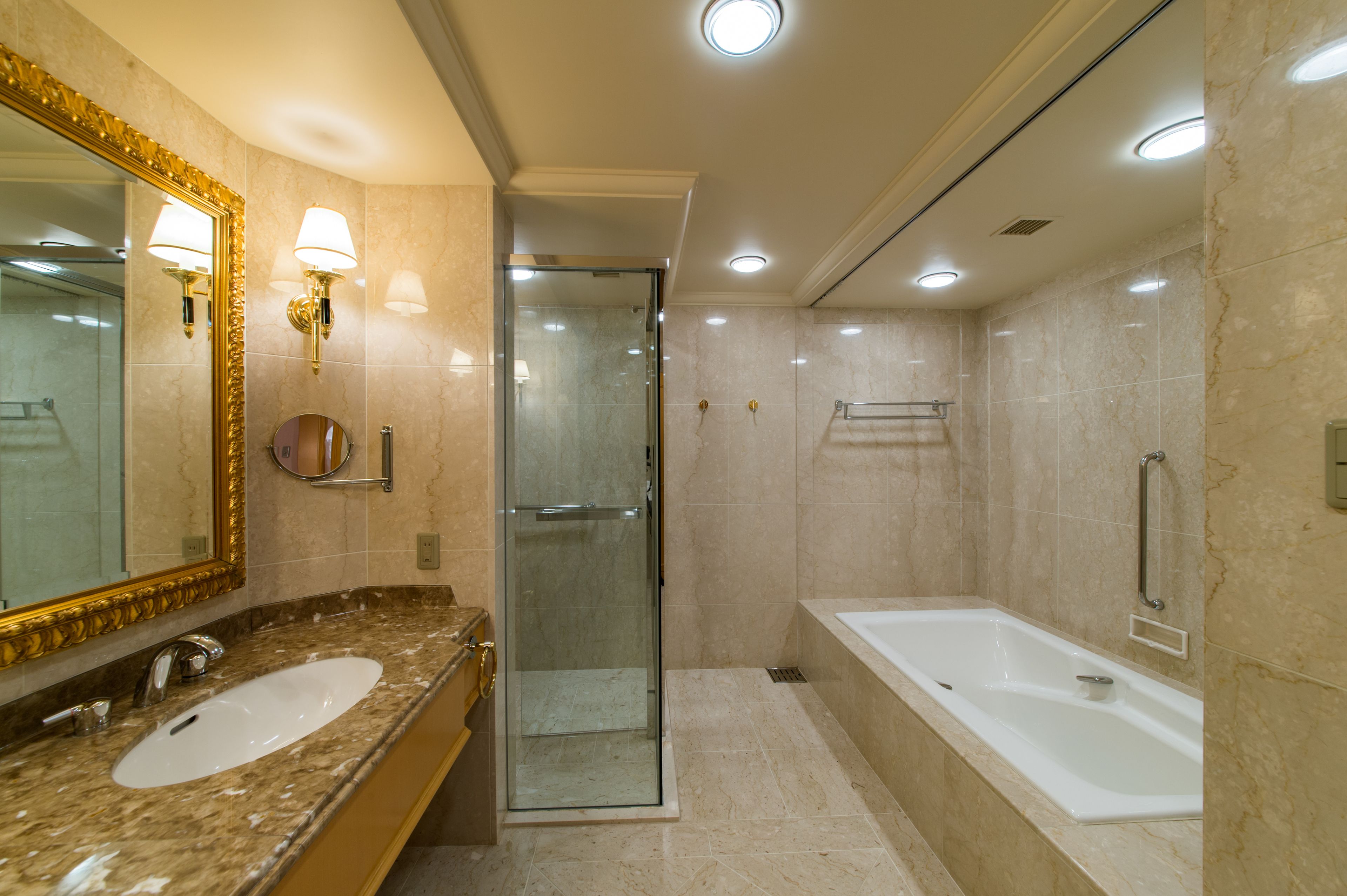Een moderne badkamer met een grote spiegel, twee wasbakken, een douche met glazen wand en een vrijstaand bad.