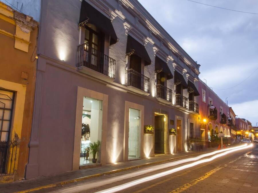 A street view of a building with a balcony, a door, and a window.