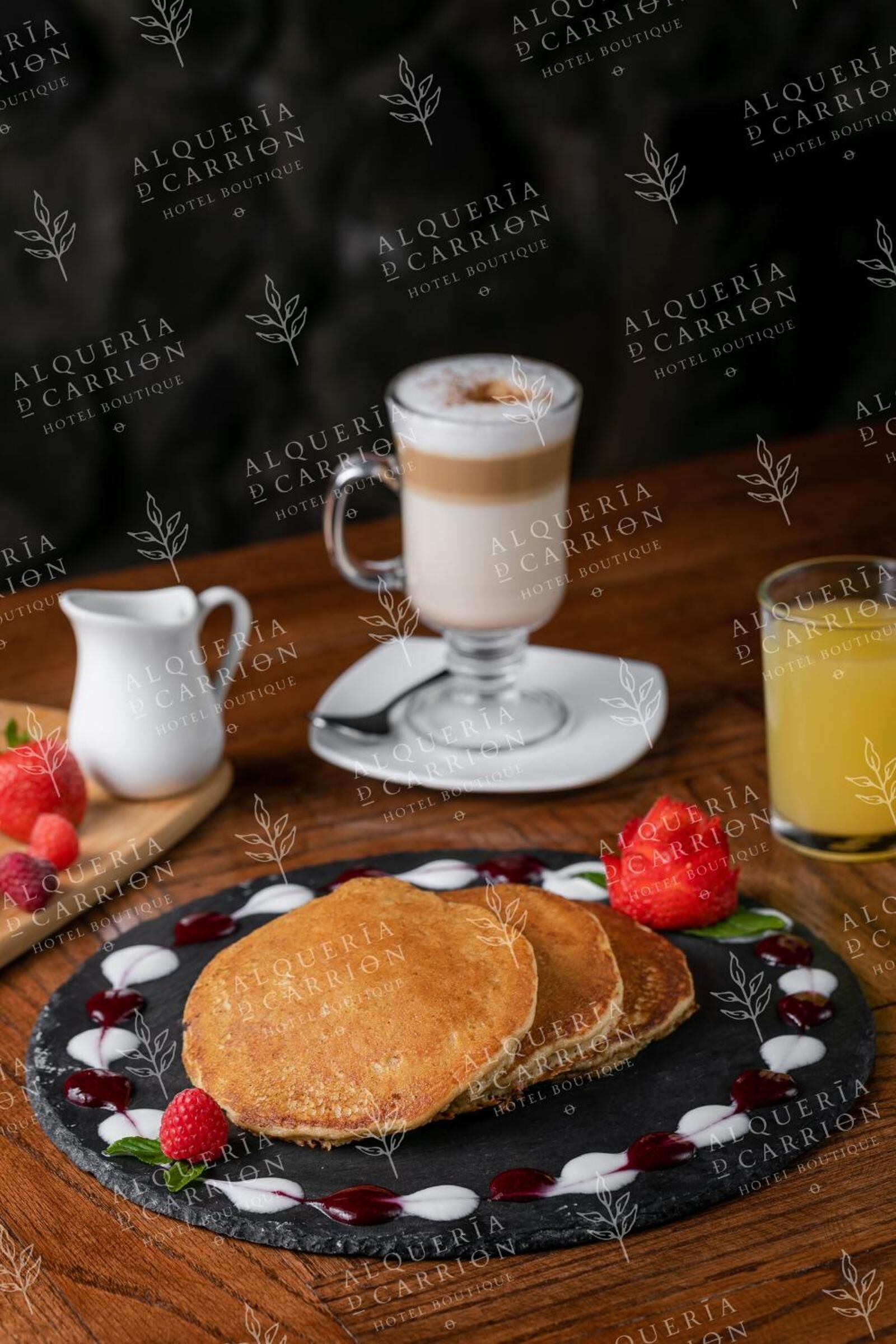 Een ontbijtje met pannenkoeken, een koffieglas en een melkkan op een houten tafel.