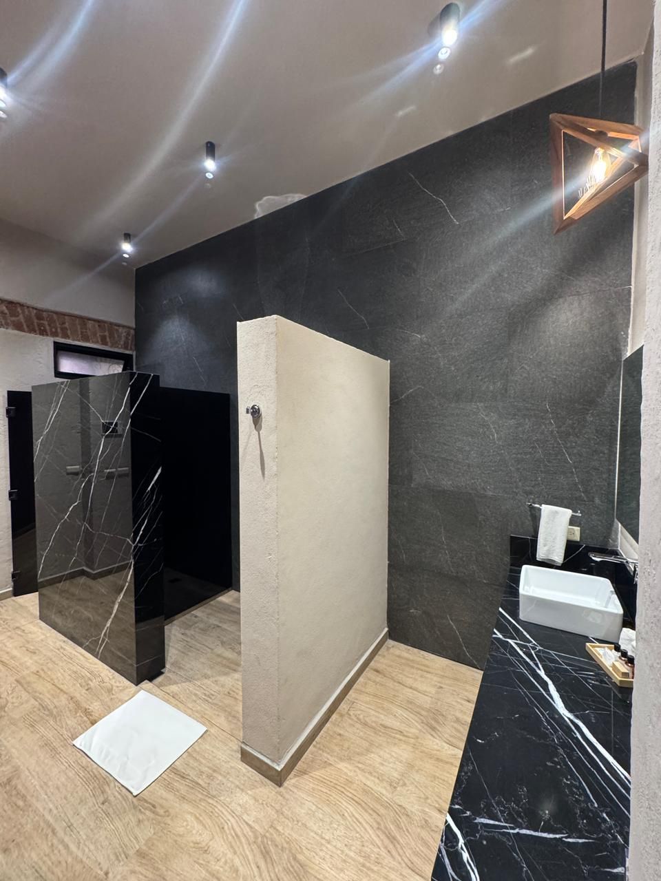 Une salle de bain moderne avec un meuble-lavabo en marbre noir, une serviette blanche et un miroir.