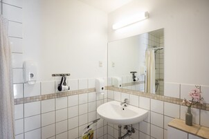 Un baño con lavamanos blanco, un espejo y una ducha.