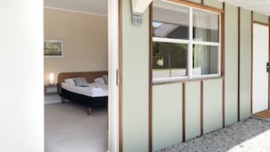 Une chambre à coucher avec un lit, une table de chevet et une fenêtre donnant sur l’extérieur.