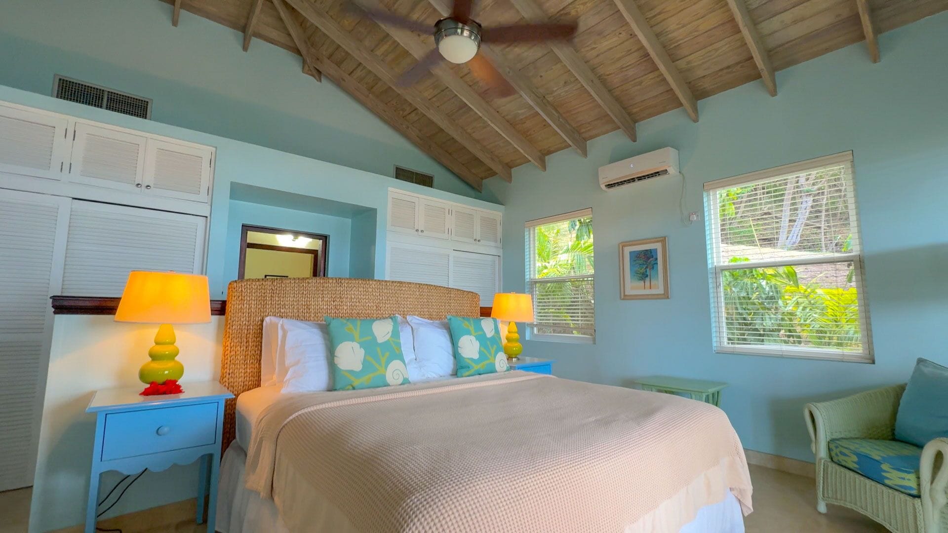 A bedroom with a bed, two nightstands, a ceiling fan, and a window with blinds.