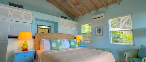 A bedroom with a bed, two nightstands, a ceiling fan, and a window with blinds.