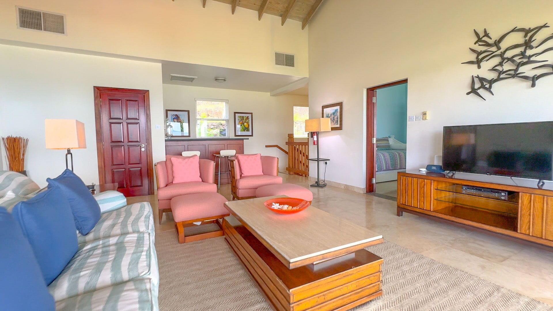 A spacious living room with a sofa, armchairs, a coffee table, and a TV.