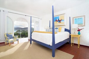 Un dormitorio con cama, una silla, una mesita y vistas al exterior.