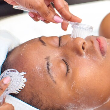 A person receiving a facial treatment with a brush and a device.
