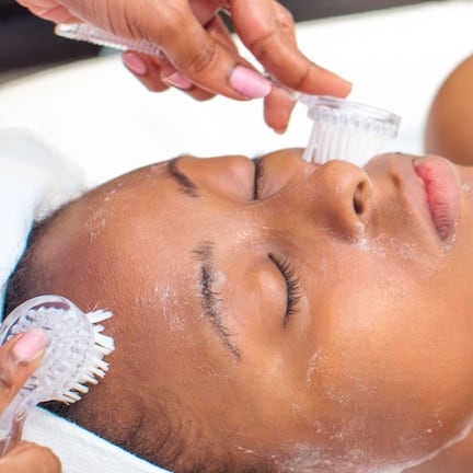 A person receiving a facial treatment with a brush and a device.