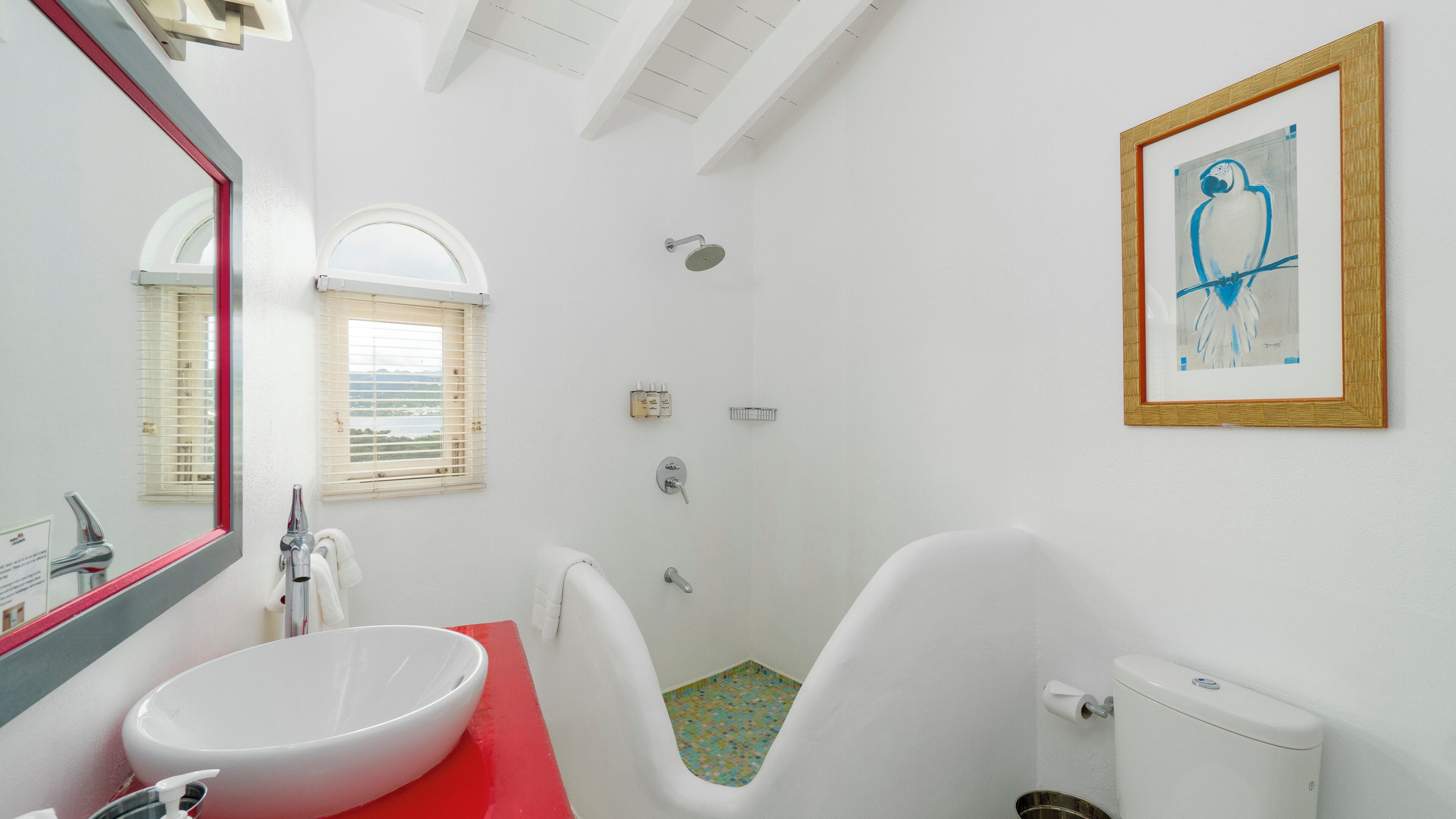 Un baño con un lavabo blanco, encimera roja, ducha e inodoro.