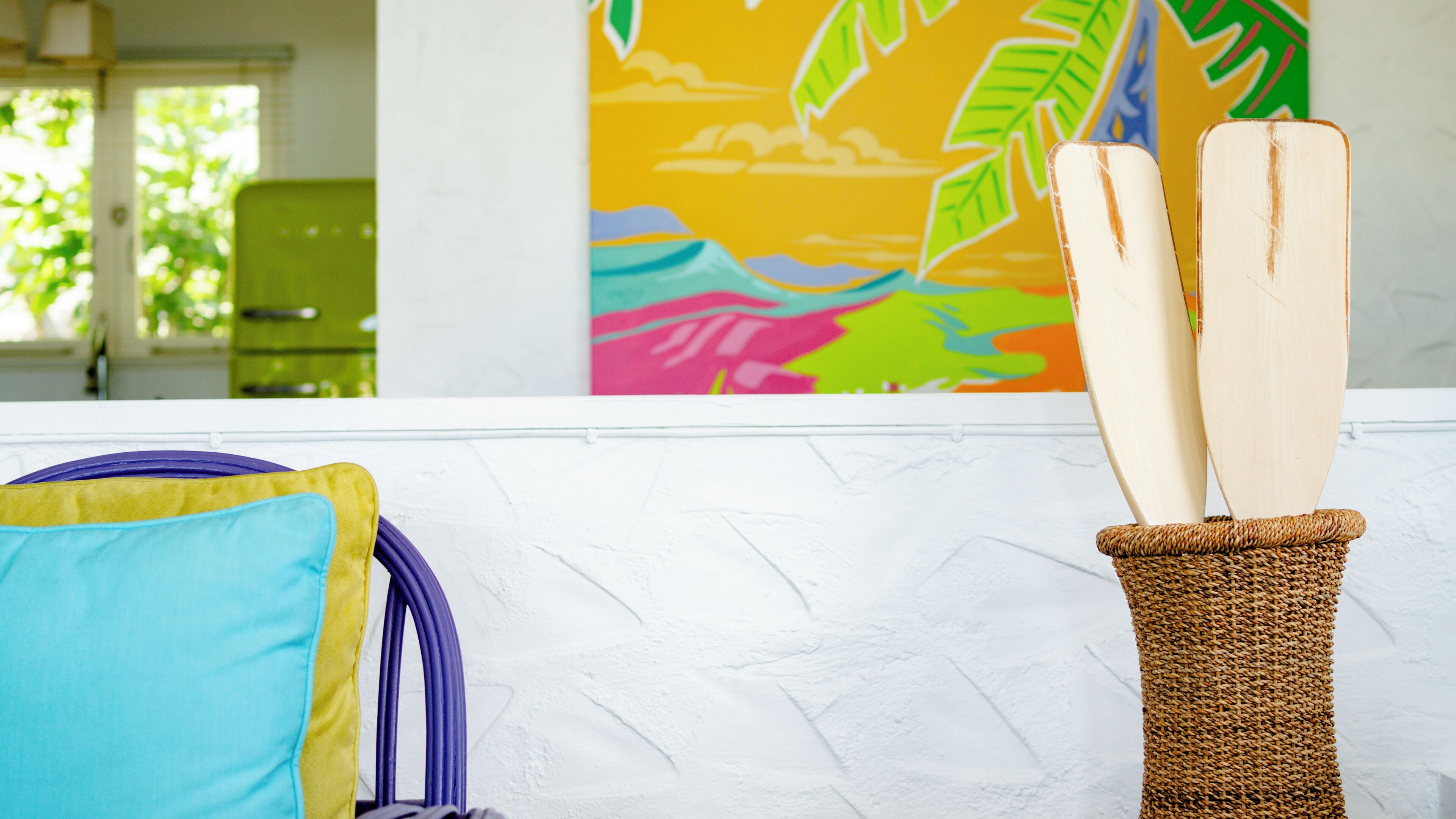 A white textured wall with a woven basket containing two wooden paddles.