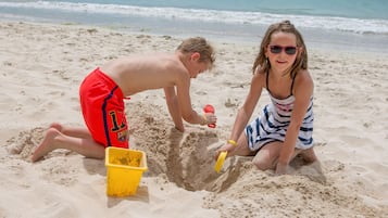 Children can play and dig in the sand on this beach, with the ocean waves gently lapping in the background.