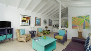 A spacious living room with a television, colorful furniture, and artwork on the walls.
