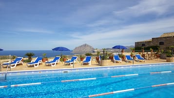 Una piscina al aire libre de temporada, sombrillas