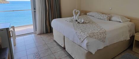 Un cuarto de hotel con una cama grande, un escritorio y vista al mar.