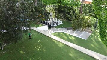 A chessboard set up on a grassy lawn with a hedge in the background.