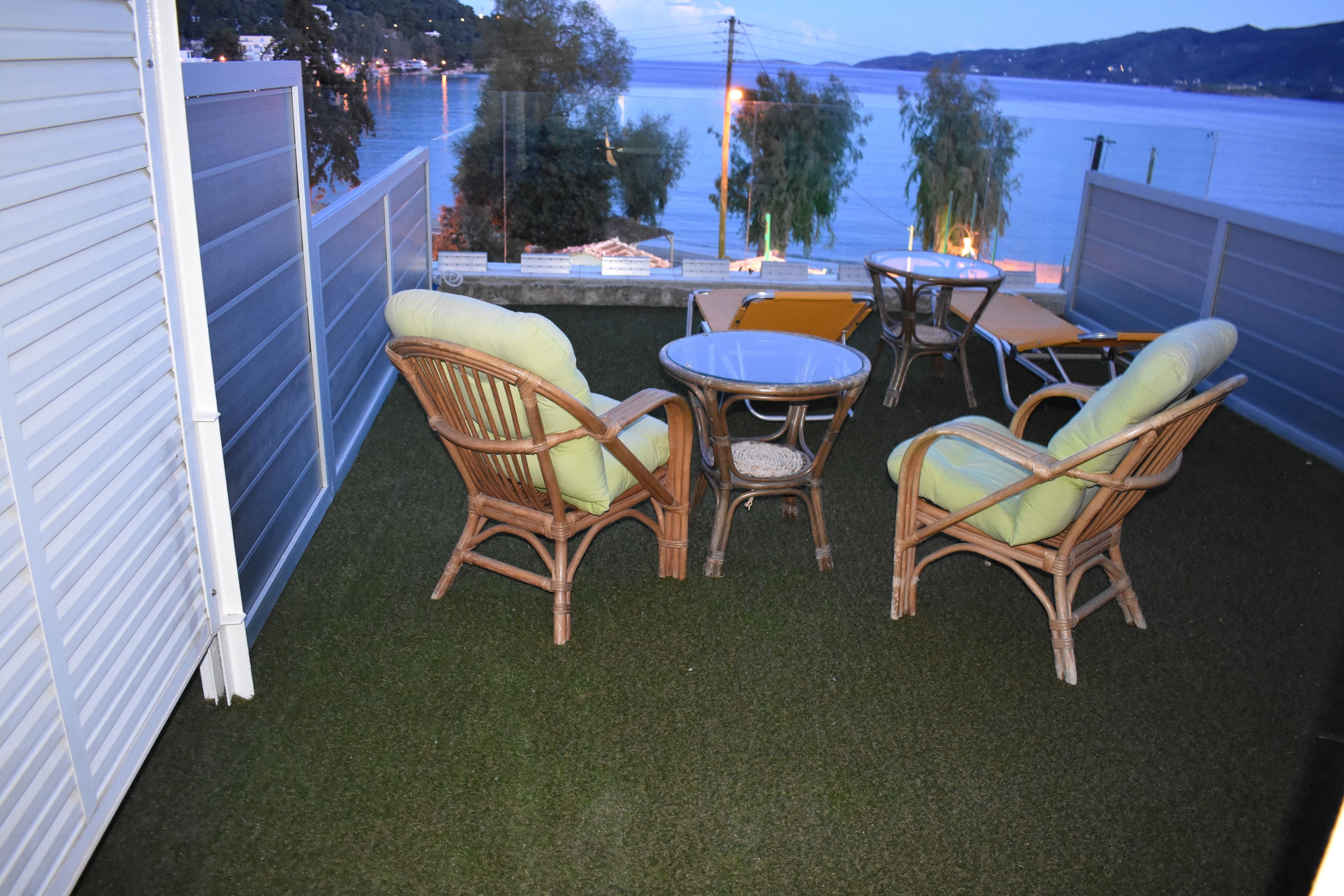 A balcony with artificial grass, wicker furniture, and a view of the water.