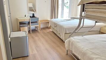 Habitación de hotel con dos camas, un escritorio, una silla, un televisor y un ventilador de techo.