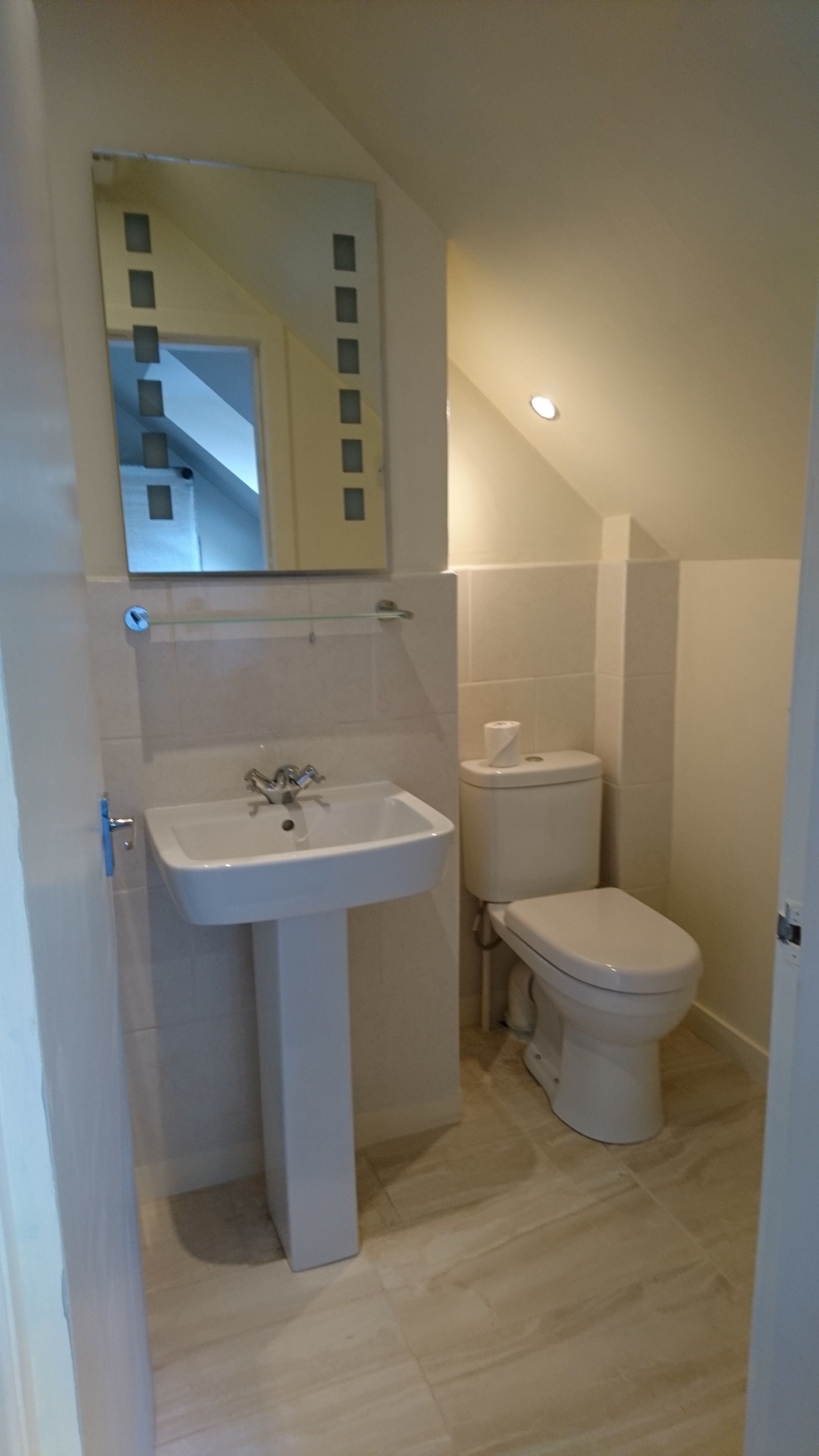 Een kleine badkamer met een wit wastafel, toilet en spiegel.