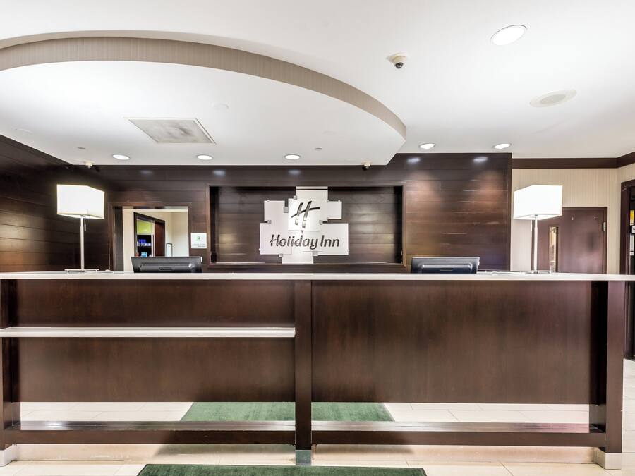 A reception desk with a sign reading 'Holiday Inn' and a security camera on the ceiling.