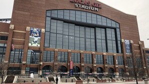 Lucas Oil Stadium with a large brick facade, multiple entryways, and a prominent American flag. - Holiday Inn Indianapolis Downtown by IHG (Indianapolis)