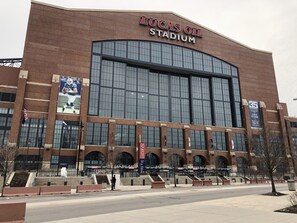 Lucas Oil Stadium with a large brick facade, multiple entryways, and a prominent American flag. - Holiday Inn Indianapolis Downtown by IHG (Indianapolis)