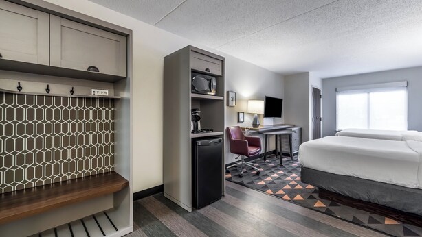 A hotel room with a bed, desk, chair, and a kitchenette. - Holiday Inn Indianapolis Downtown by IHG (Indianapolis)