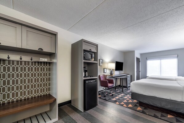 A hotel room with a bed, desk, chair, and a kitchenette. - Holiday Inn Indianapolis Downtown by IHG (Indianapolis)