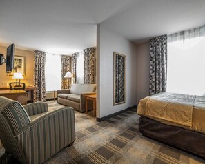 A hotel room with a bed, a sofa, a chair, a desk, and a TV. - MainStay Suites Casper (Casper)